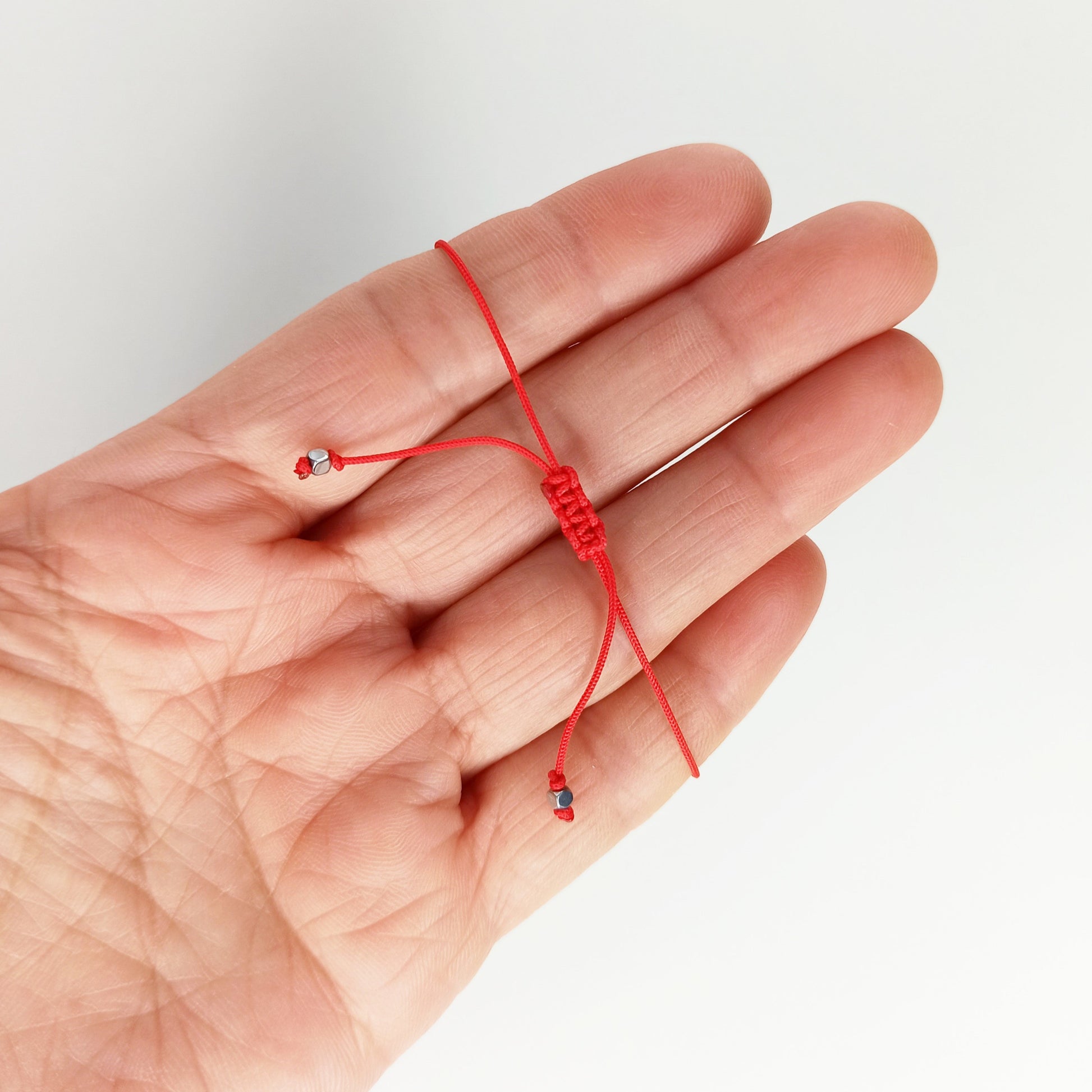 Esta es una pulsera ajustable elaborada en hilo color rojo de 0.50 mm. Está hecha en 50% algodón y 50% poliéster. El nudo corredizo de macramé te permite ajustarla como más te guste.