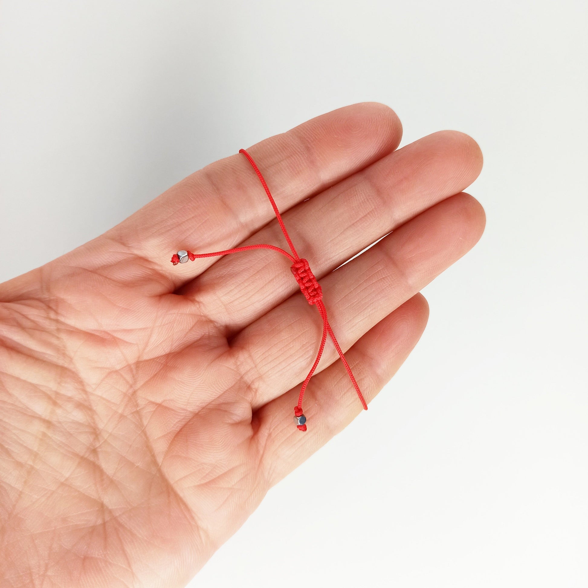 Pulsera de cordón rojo con nudo macramé que se puede deslizar fácilmente para quitar o poner cuando quieras.