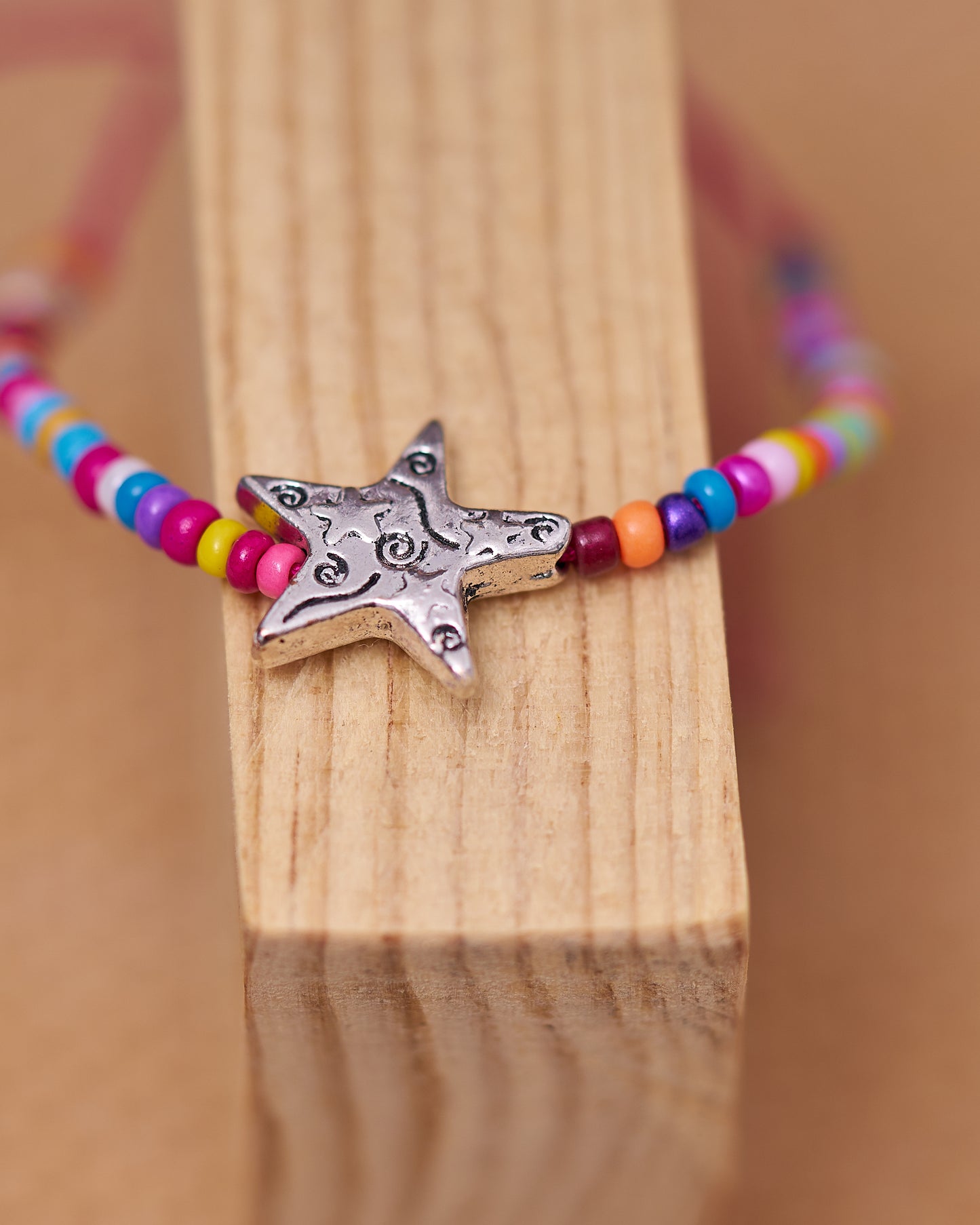 Pulsera de cuentas multicolores con estrella en plateado.