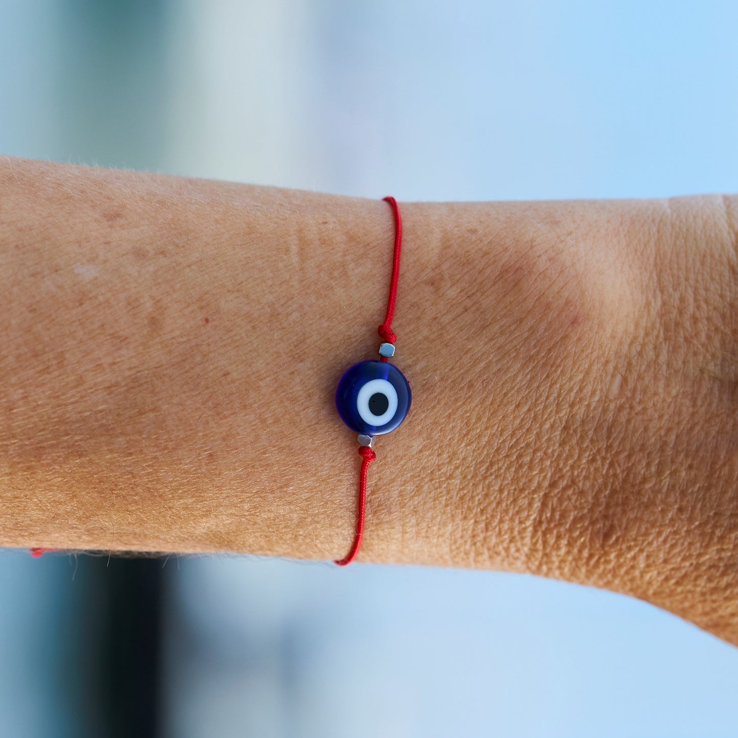 Descubre nuestra pulsera ajustable con el poderoso mal de ojo, el ojo turco protector, elaborada con hilo rojo